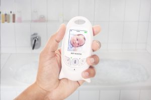 Parent checking newborn through baby monitor shortly before she takes a bath